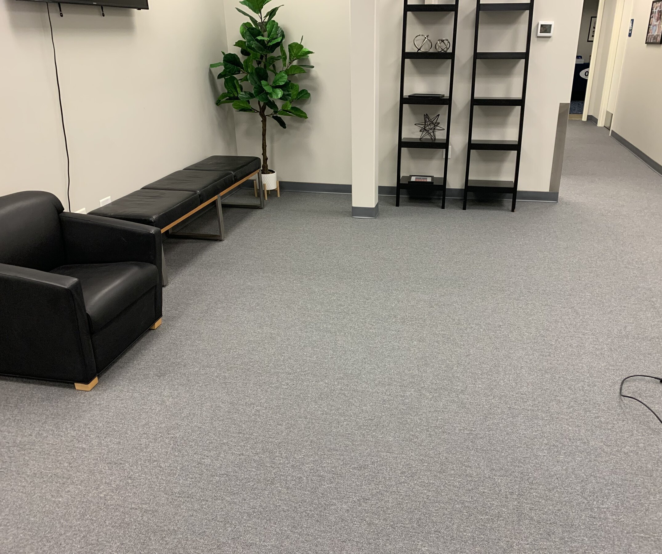 Grey commercial carpet in office lounge with bench and shelving
