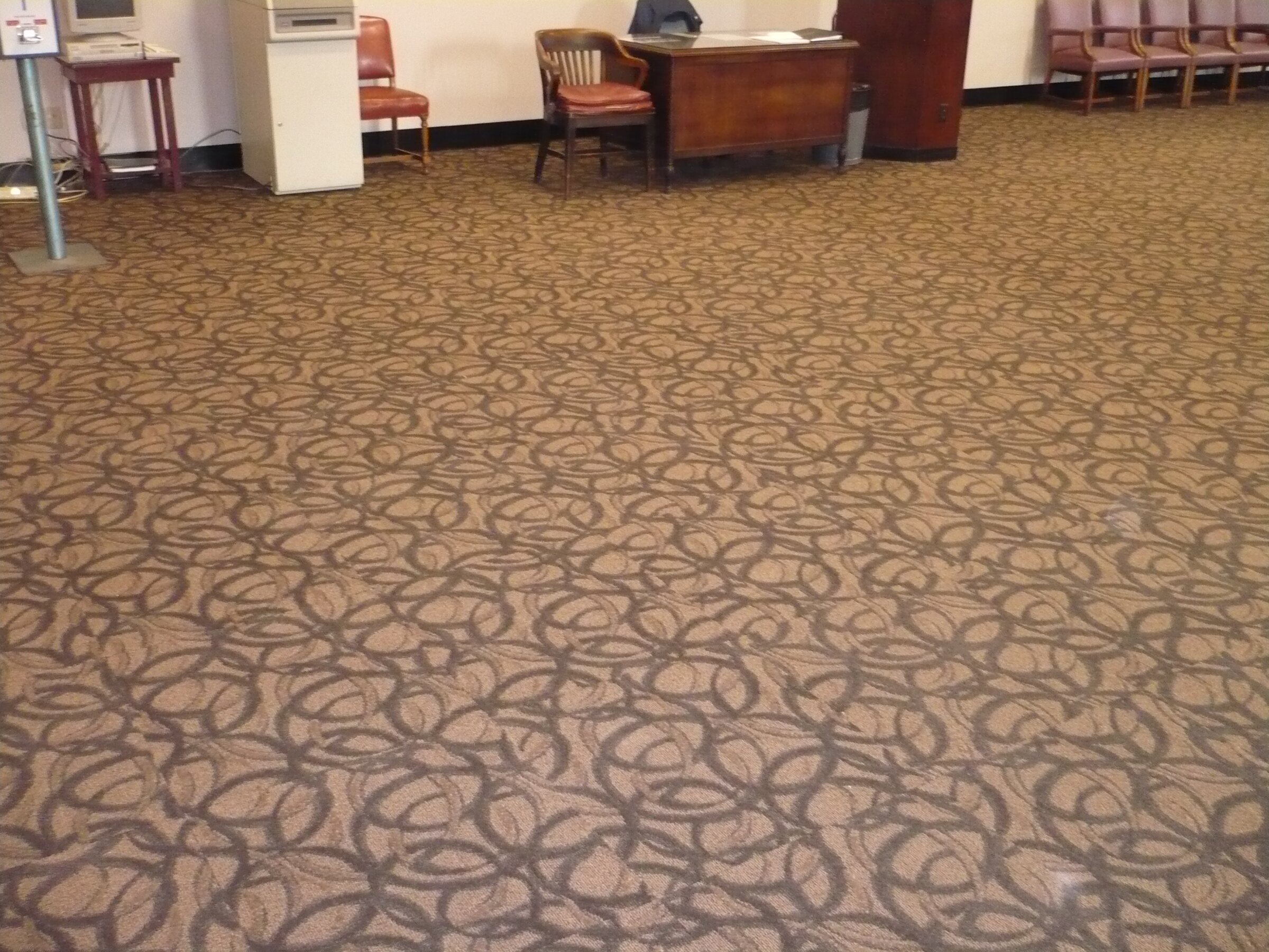 Patterned commercial carpet in office lobby with chairs and desk