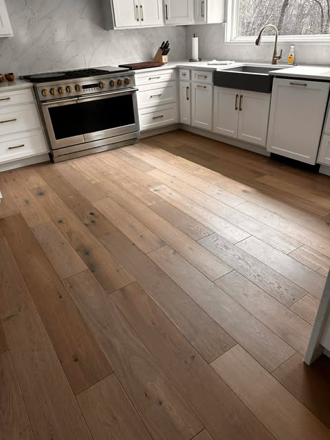 Wide plank hardwood flooring in modern kitchen with white cabinets