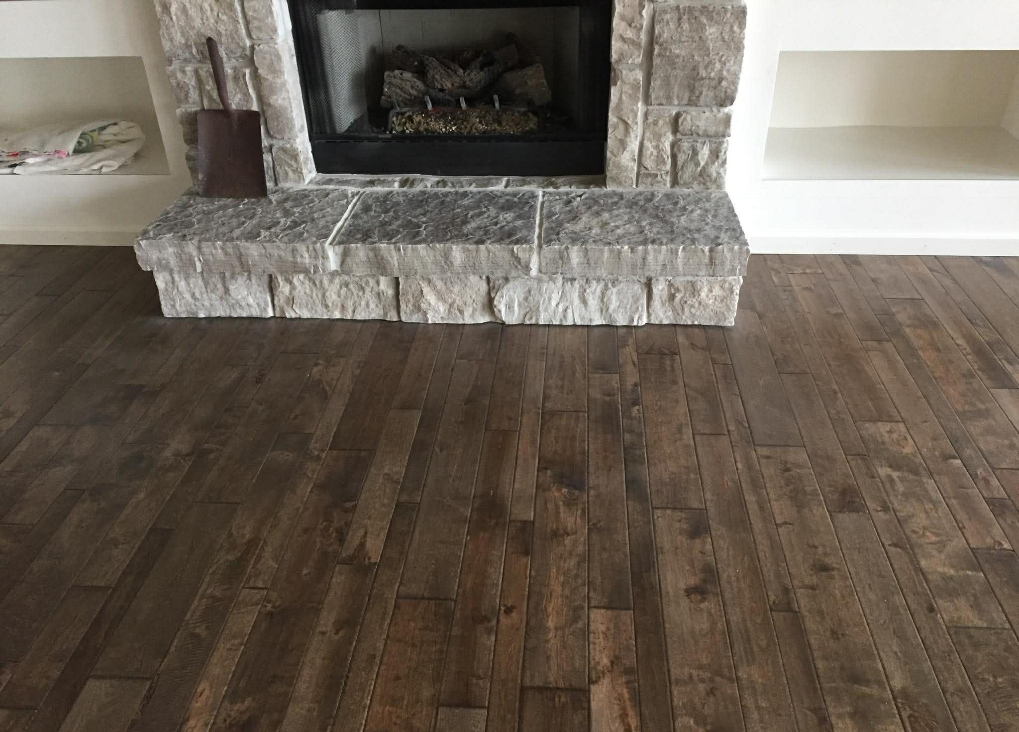 Dark hardwood flooring next to stone fireplace surround