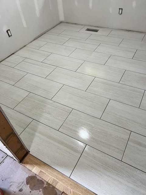 Gray tile floor installation in herringbone pattern