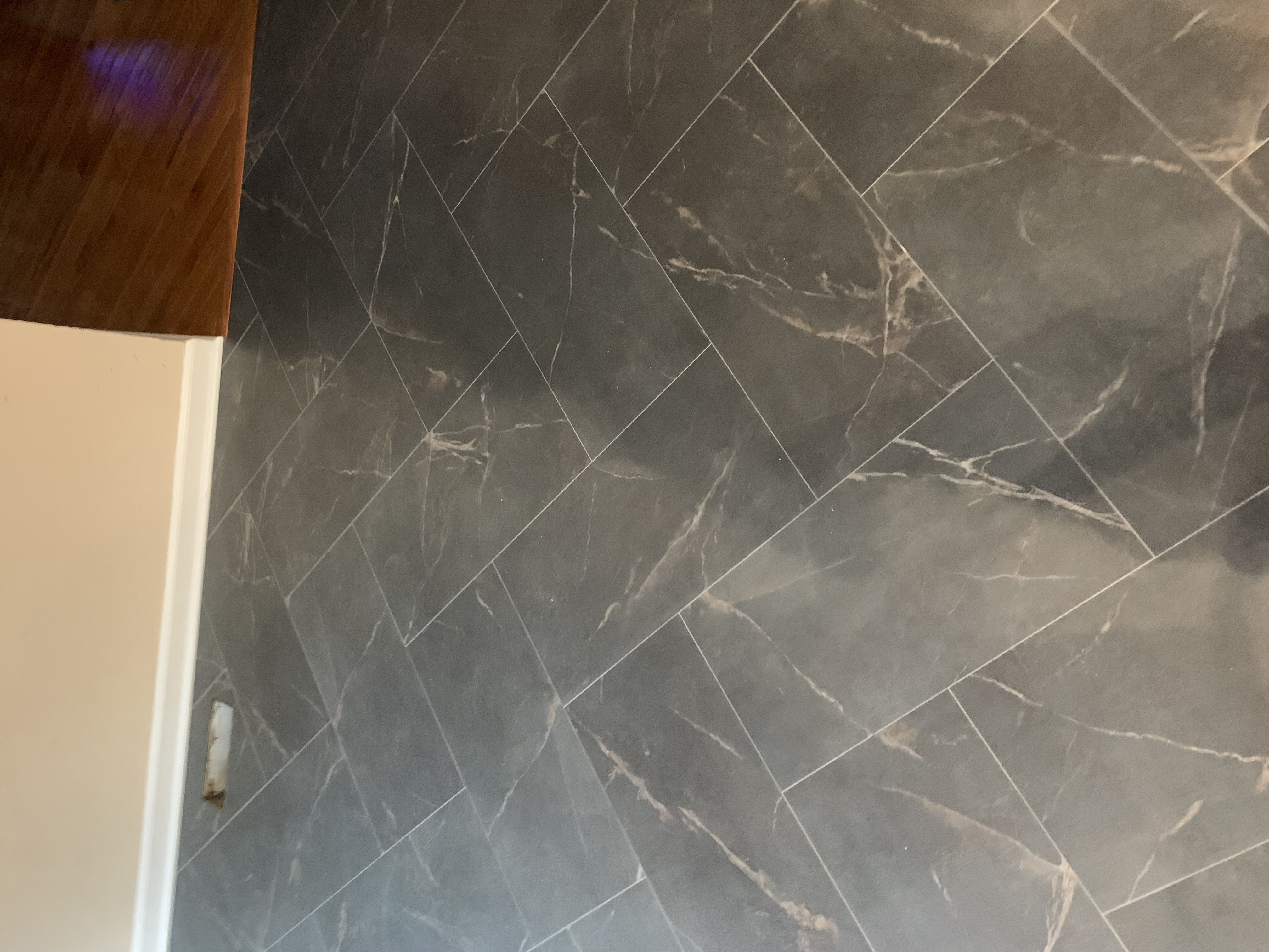 Mannington Baltic Stone Storm LVT herringbone floor transitioning to hardwood hallway