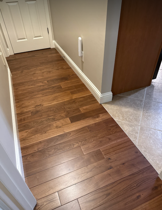 Hardwood-to-tile transition in entry hallway with crisp white baseboards