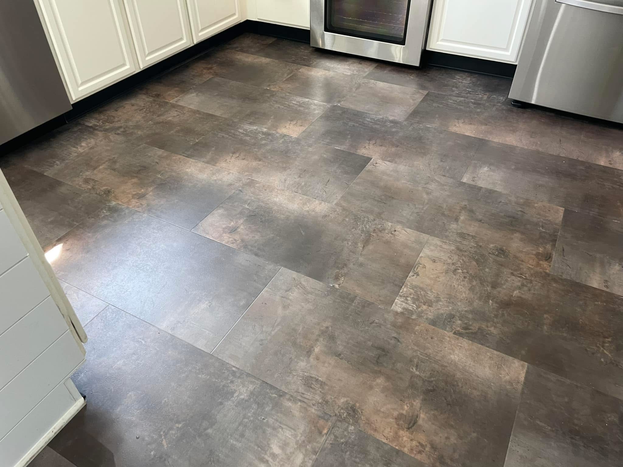 Slate-look tile kitchen flooring with white cabinets and stainless appliances
