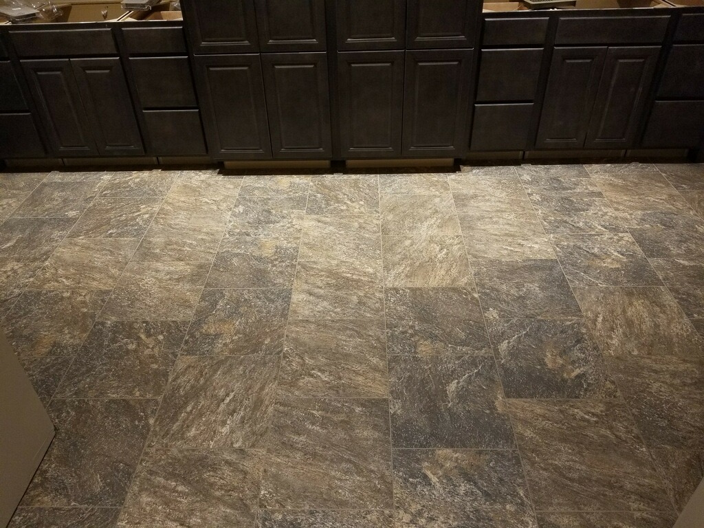 Natural stone-look tile kitchen floor with dark cabinets