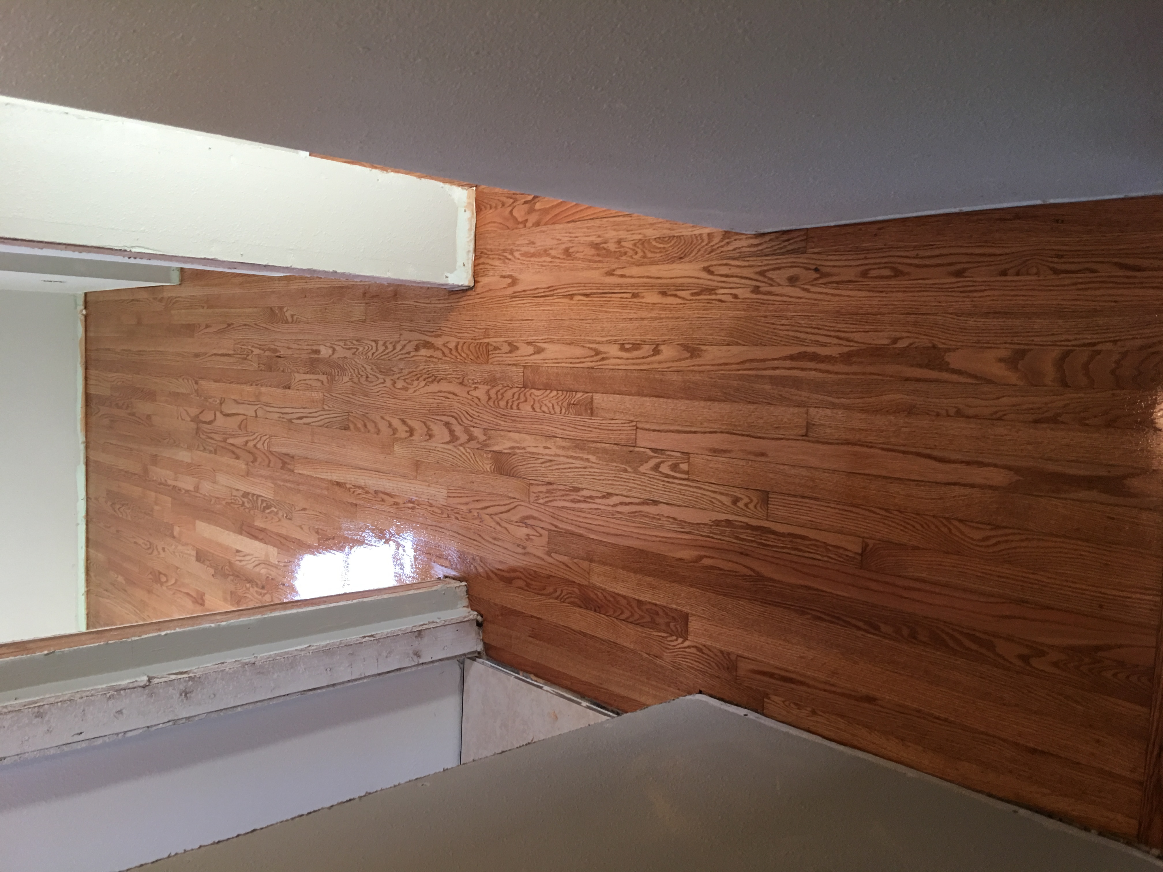 Restored hallway hardwood floor after refinishing - smooth glossy oak finish
