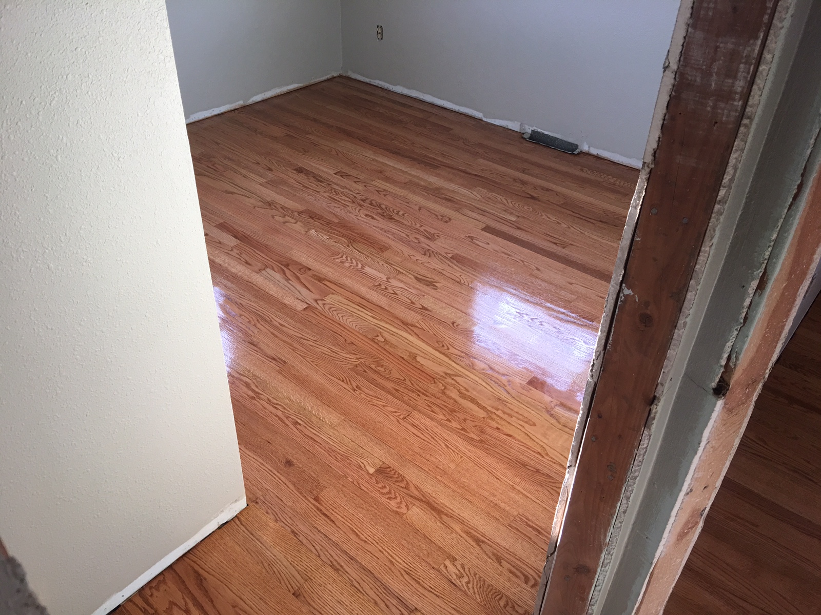 Beautifully refinished hardwood floor - same room with glossy restored finish