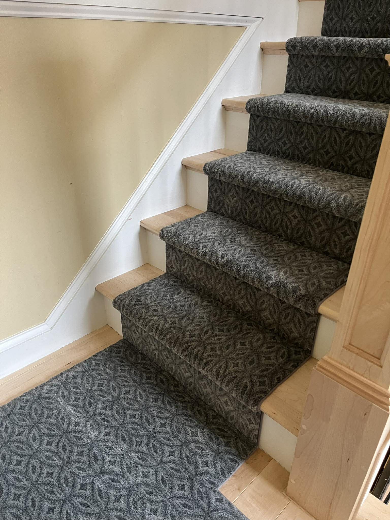 Dark geometric patterned carpet on staircase with wood treads