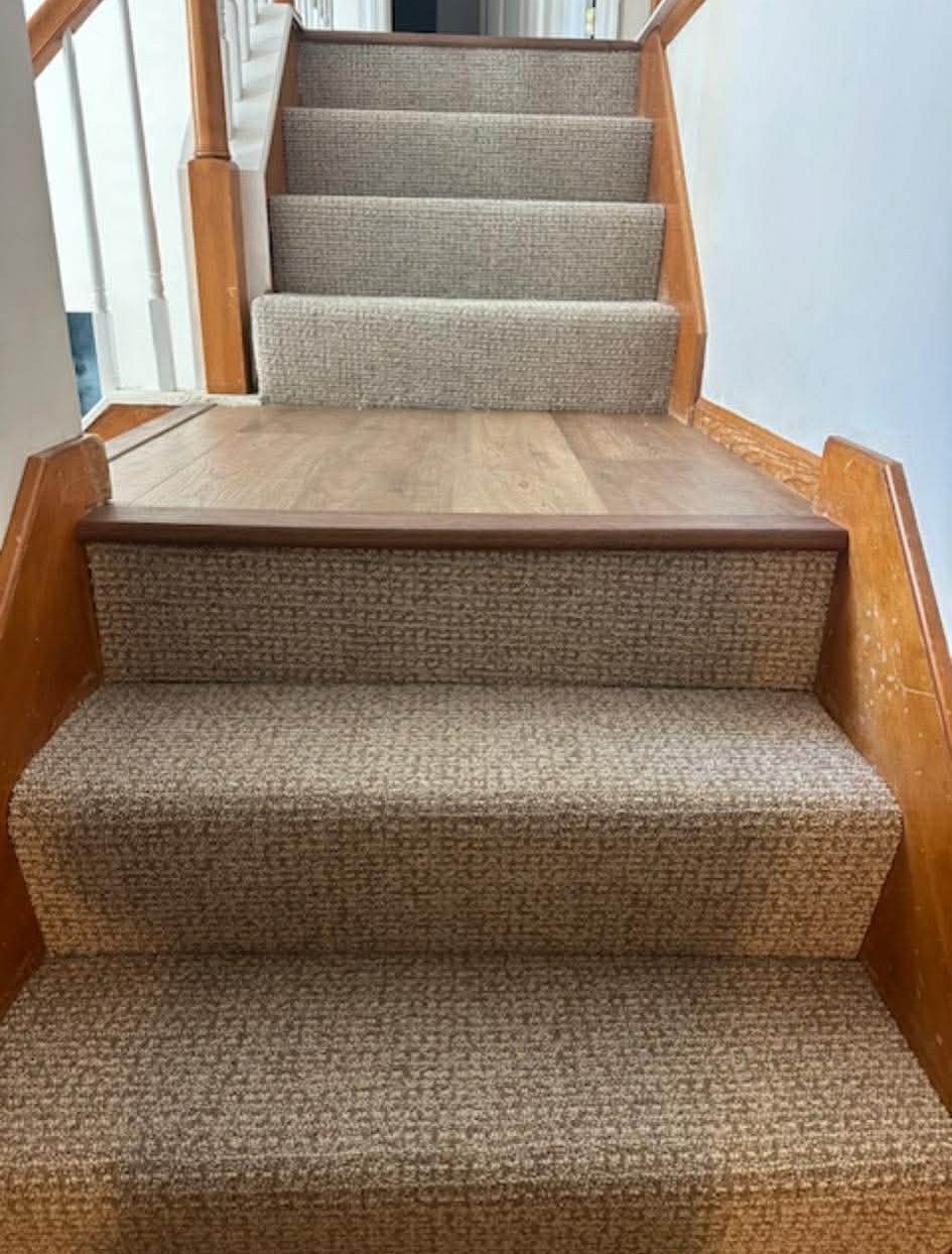 Neutral berber carpet installation on staircase with wood details