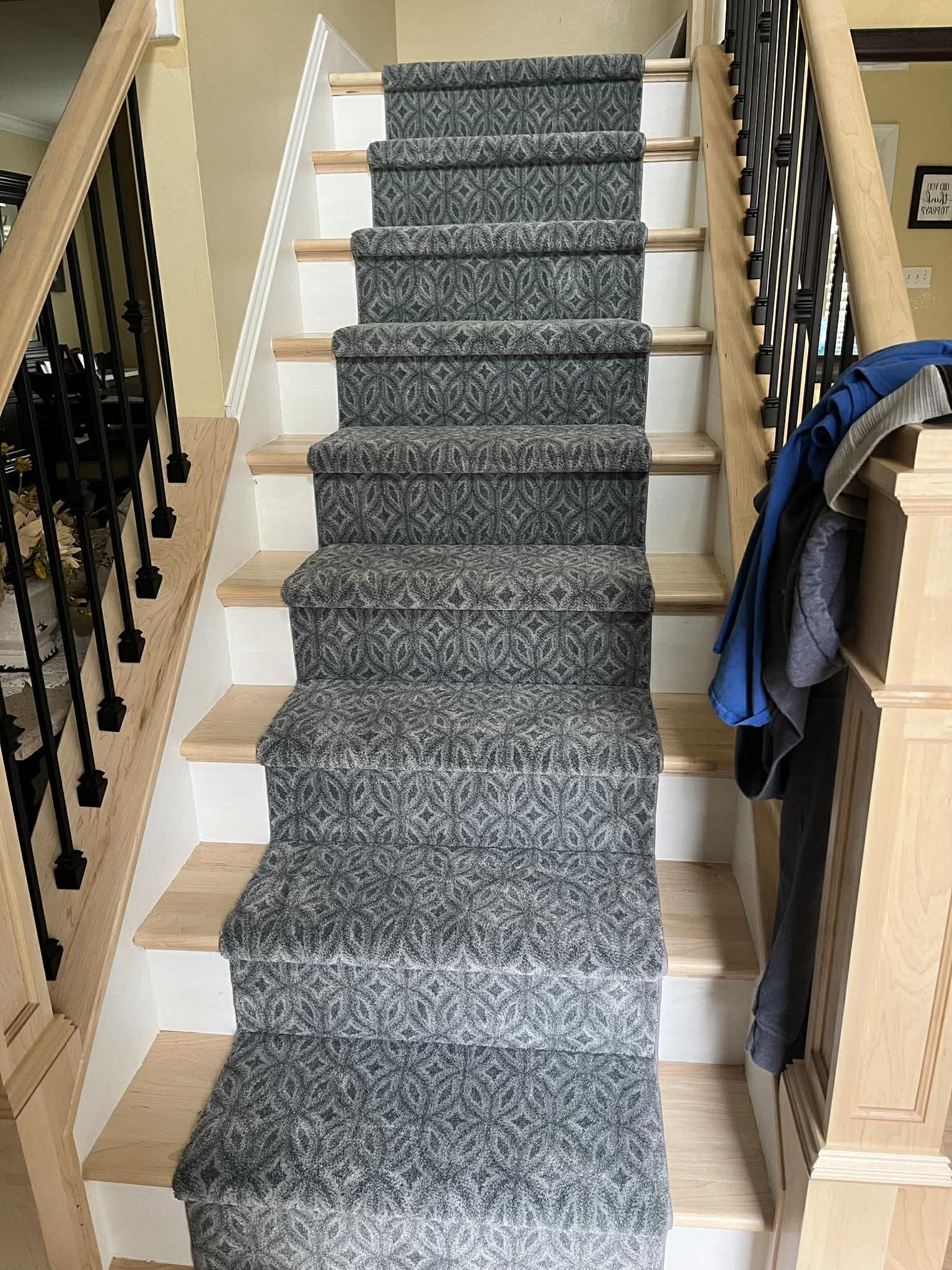 Full staircase with dark geometric patterned carpet and black balusters